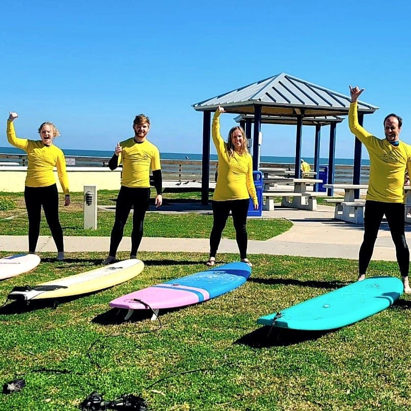 Four students in yellow rash guards celebrating after a lesson