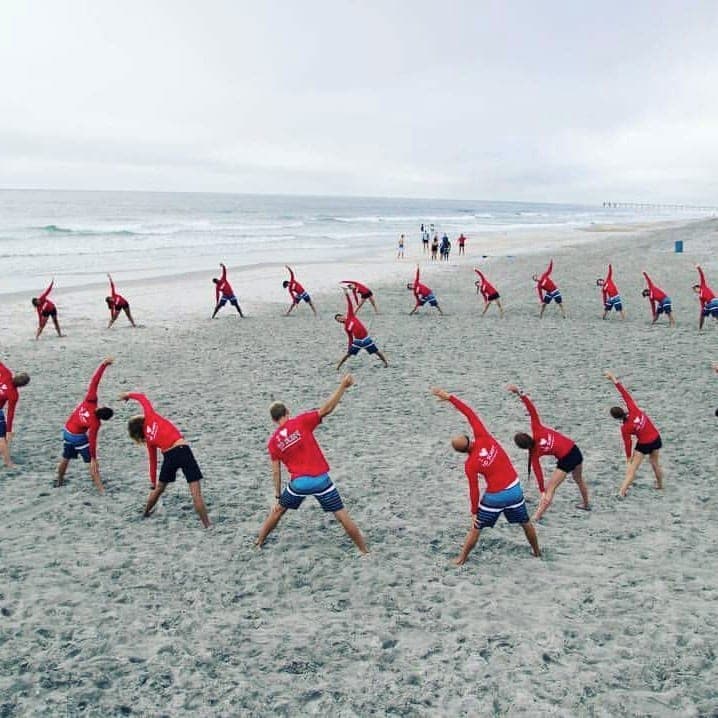Wide view of a lesson group stretching on the beach
