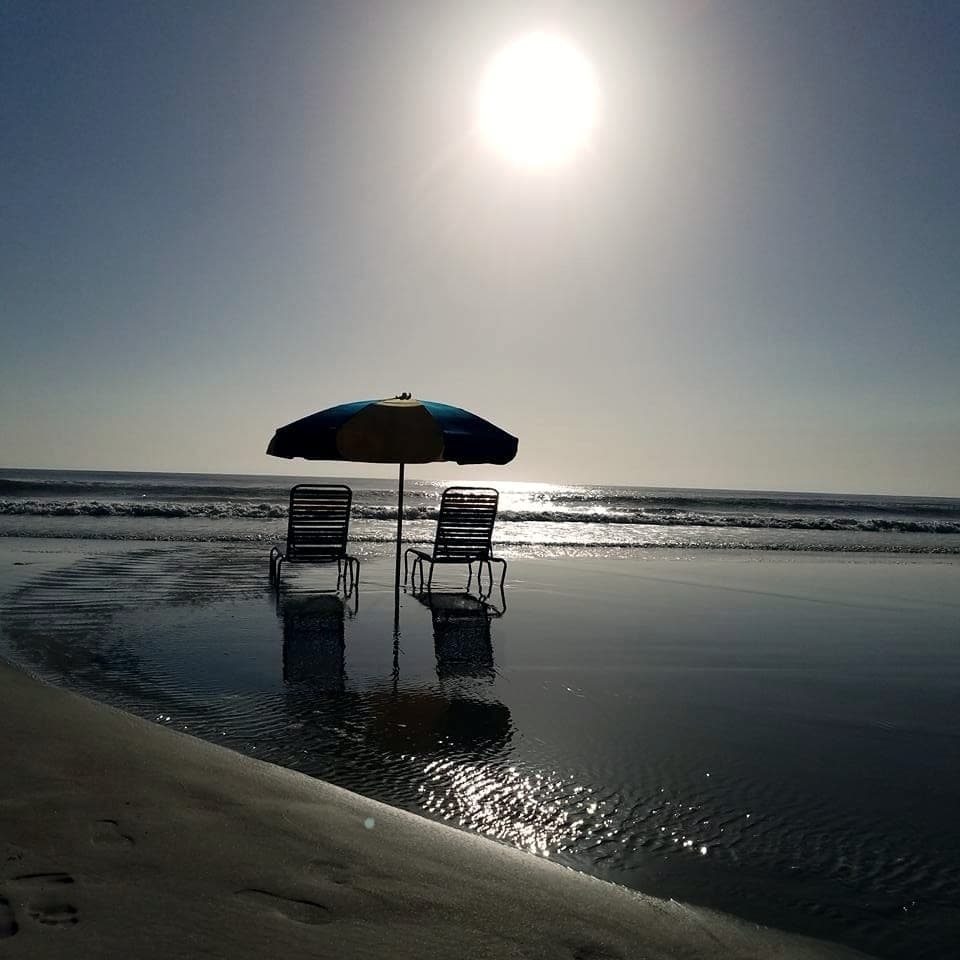 Beach umbrella and chairs on a glassy sunrise morning