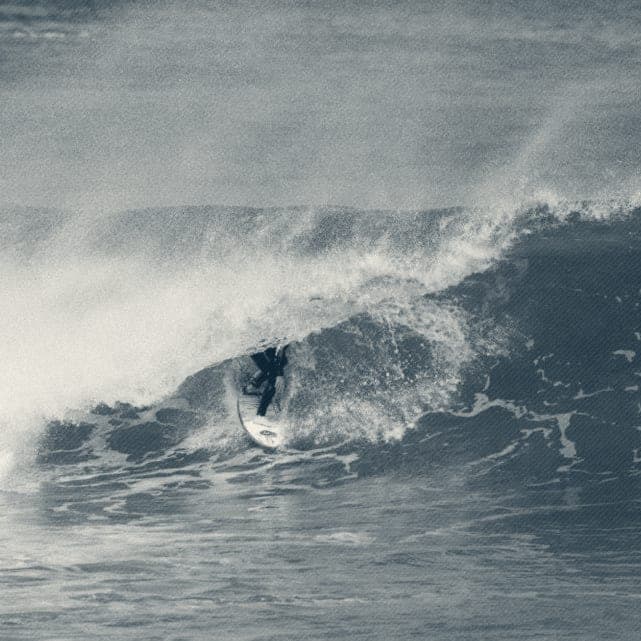 Ryan Ragan pulling into a glassy green barrel in a wetsuit