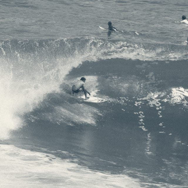 Ryan Ragan turning hard under the lip while surfers paddle behind
