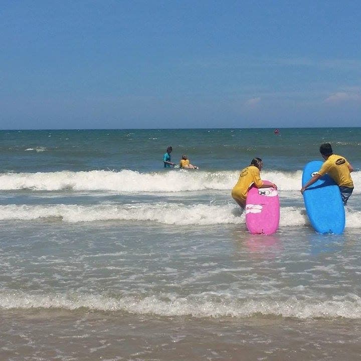 Instructors carrying soft-top boards into the surf