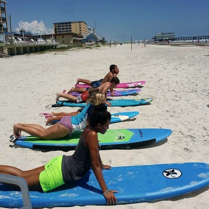 Lesson group running pop-up drills on colorful soft-top boards