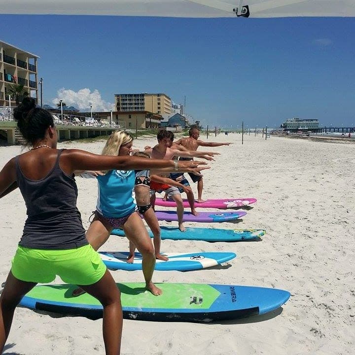 Class practicing their surf stance on boards in the sand