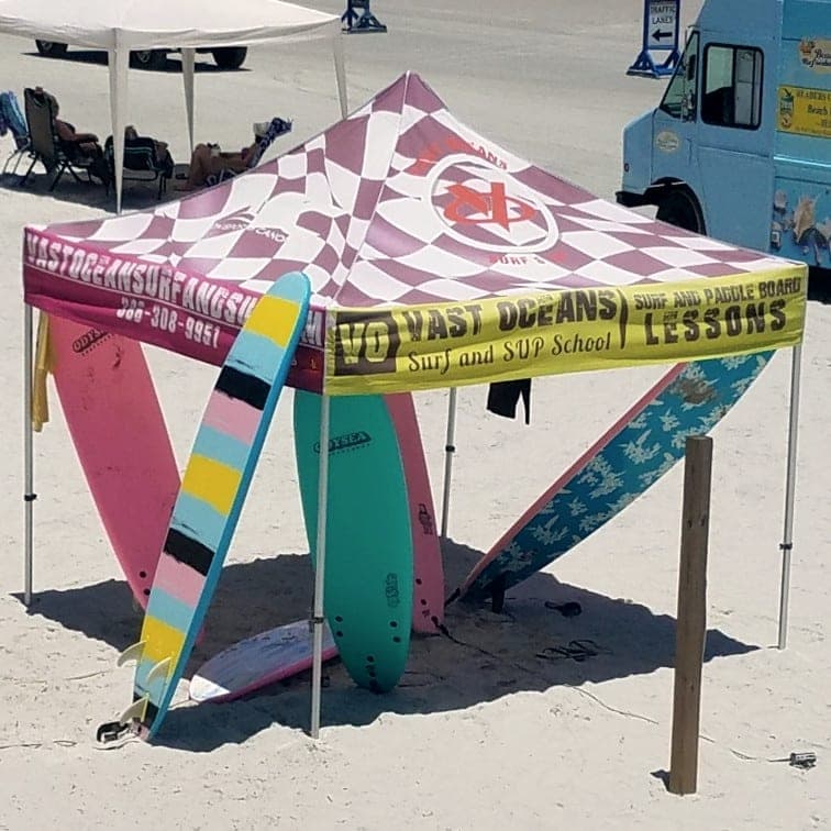 The Vast Oceans lesson tent and soft-top boards on the sand