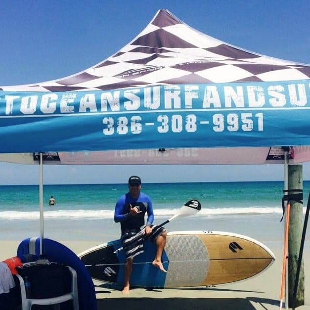 Instructor with a stand up paddle board under the lesson tent