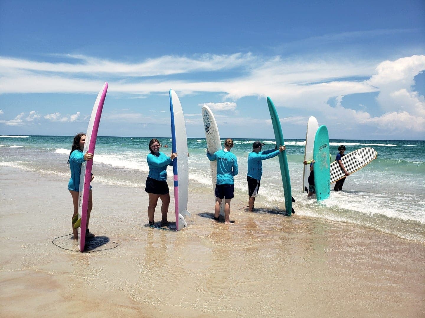 A lesson group holding boards upright at the shoreline, seen from a distance