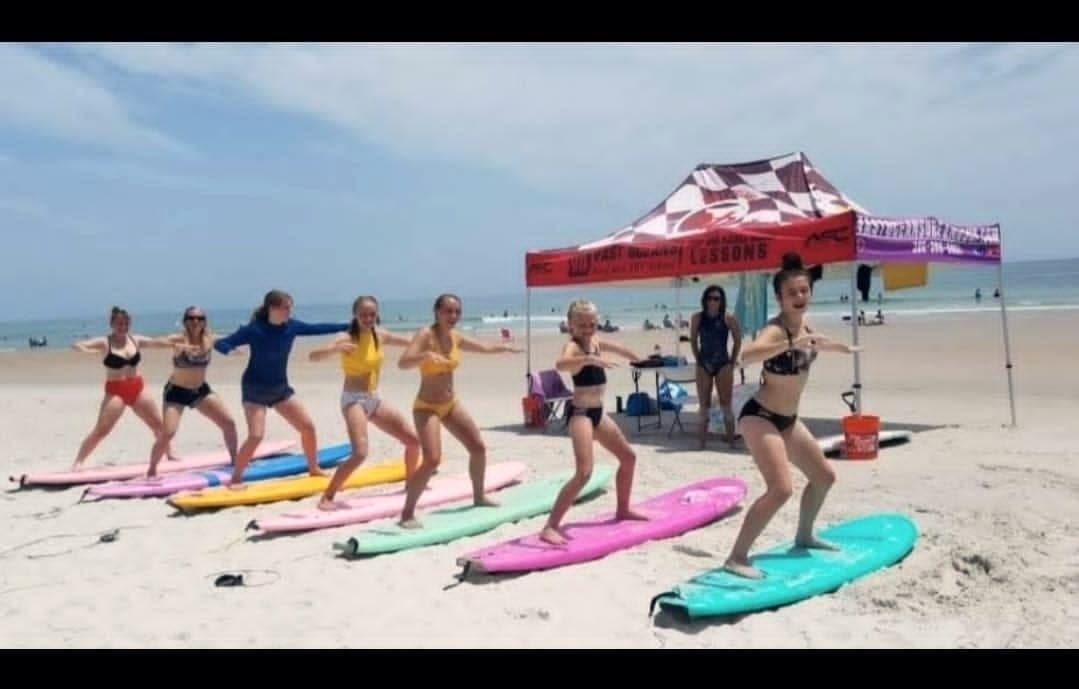 A line of students practising the pop-up on boards laid out on the sand