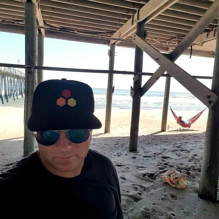 Ryan Ragan in a cap and sunglasses in the shade under a pier