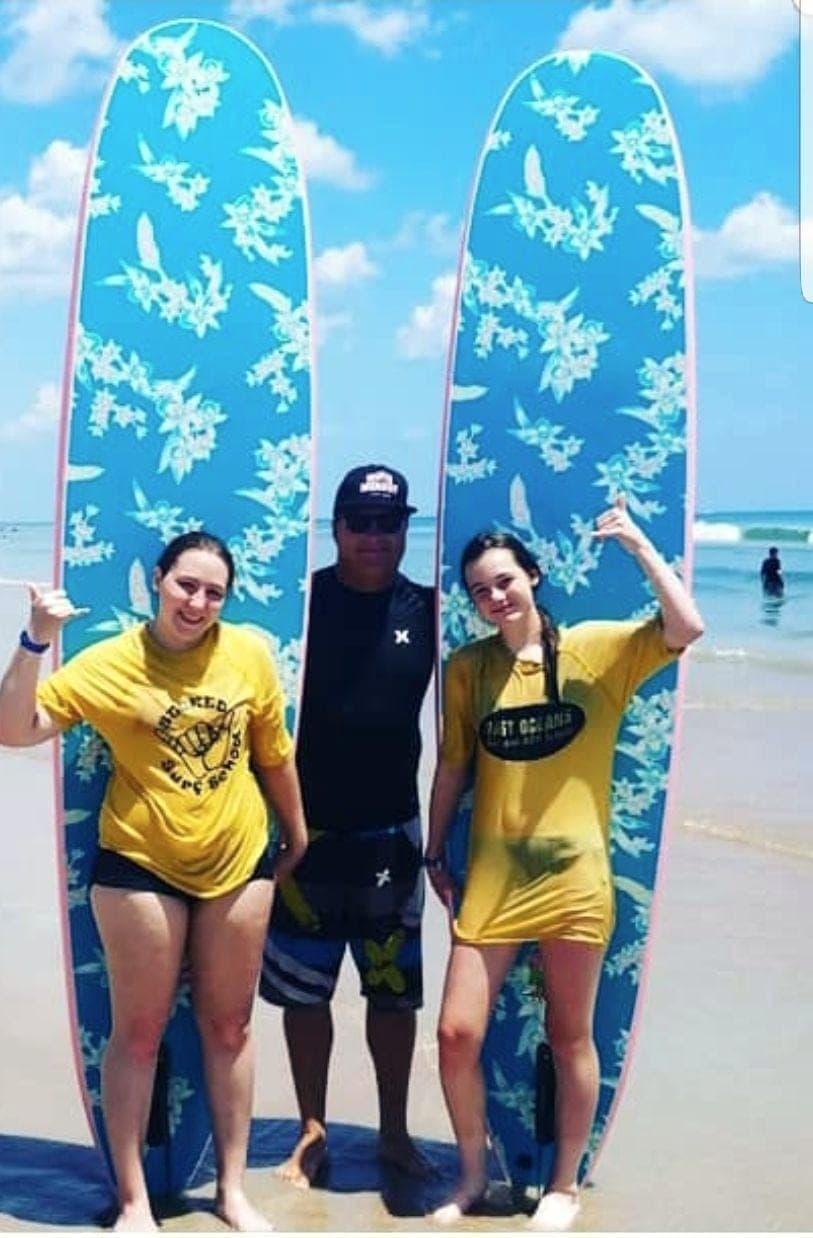 Two students in school shirts and an instructor standing between upright boards