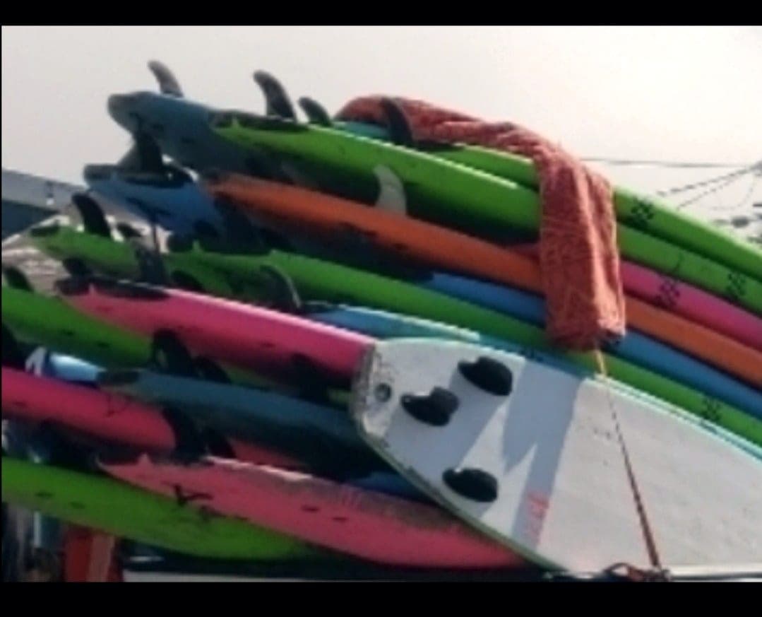 A stack of coloured soft-top surfboards with a towel laid over them