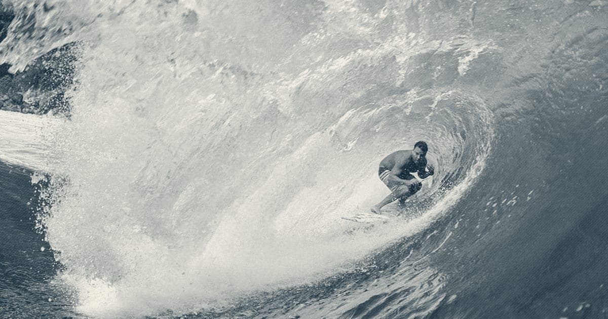 Ryan Ragan crouched deep inside a large turquoise barreling wave